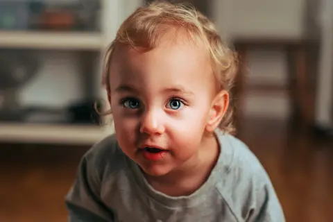 Niebieskie, uciekające oko dziecka z blond lokami, patrzy z zaciekawieniem.