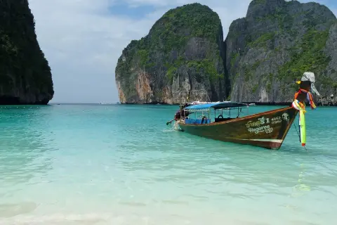Łódź kołysze się na turkusowych wodach Maya Bay, otoczonej stromymi, porośniętymi zielenią klifami.