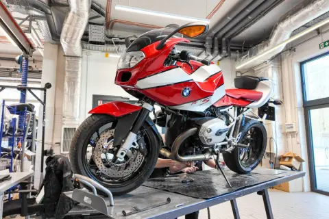 Czerwono-biały motocykl BMW R1200S na podnośniku w warsztacie.