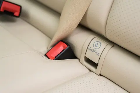 Widoczny symbol ISOFIX na jasnej tapicerce fotela samochodowego to klucz do bezpiecznego montażu fotelika.