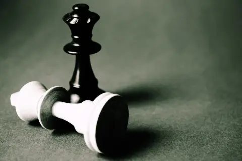 Czarna królowa stoi nad pokonaną białą figurą. To obraz strategii i triki szachowe.