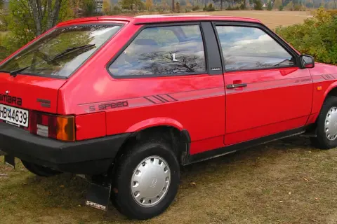 En röd Lada Samara står parkerad på en gräsmatta. Bilen har en "5 SPEED"-dekal på sidan.