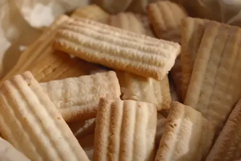 Stos ciastek ze skwarkami, pieczonych na papierze, z charakterystycznymi prążkami.