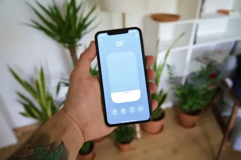 Main tenant contrôle la température de sa maison avec une application tado homekit sur son smartphone.