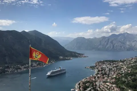 Montenegro backpacking: Fahne weht über Bucht mit Kreuzfahrtschiff und Bergen. Traumhafter Ausblick!