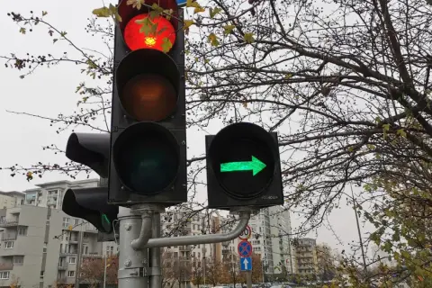 Sygnalizacja świetlna z czerwonym światłem na górze i zieloną strzałką w prawo.