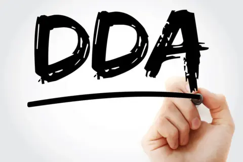 Ręka pisze markerem "DDA", symbolizując objawy dorosłych dzieci alkoholików.