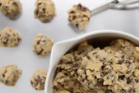 Frisch geformte american cookies mit Schokostückchen auf einem Backblech, bereit zum Backen.