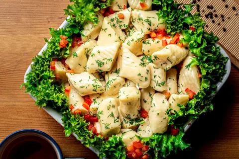 Pyszne pierogi ze szpinakiem, posypane koperkiem i papryką, otoczone sałatą. Idealne na obiad!