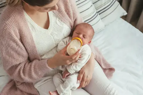 Mama karmi noworodka butelką, ucząc się jak karmić noworodka butelką.