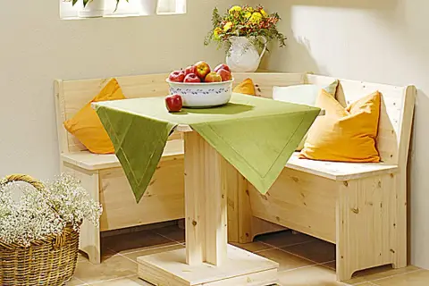 Holzige Eckbank mit Schlaffunktion selber bauen: Gemütliche Sitzecke mit Tisch, Äpfeln und Blumenkorb.