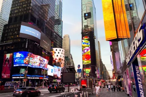 Manhattan, Nowy Jork, rozświetlony neonami i billboardami, z Żółwiami Ninja na jednym z budynków.