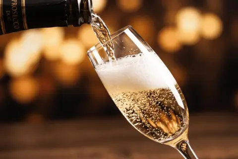 Bąbelki musującego prosecco wypełniają kieliszek, gdy jest nalewane z butelki. To jest właśnie prosecco!