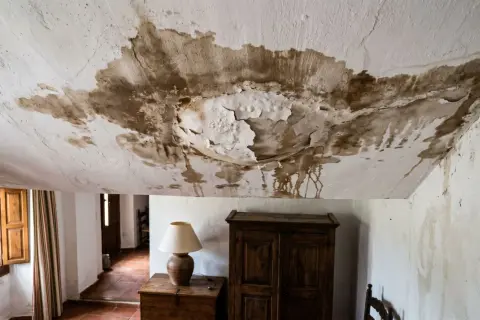 Tejado con manchas de humedad y pintura desprendida, indicando la necesidad urgente de reparar tejado.