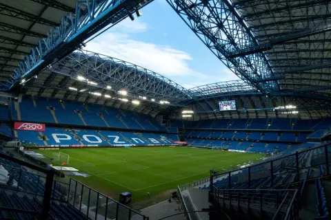 Pusta, błękitna trybuna stadionu Lecha Poznań, gotowa na przyjęcie kibiców. Pojemność stadionu robi wrażenie.