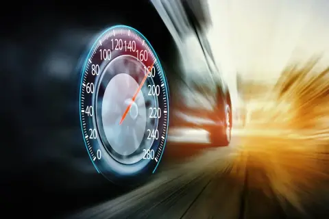 Prędkościomierz pokazuje ponad 180 km/h. Samochód pędzi drogą ekspresową, rozmazując krajobraz.