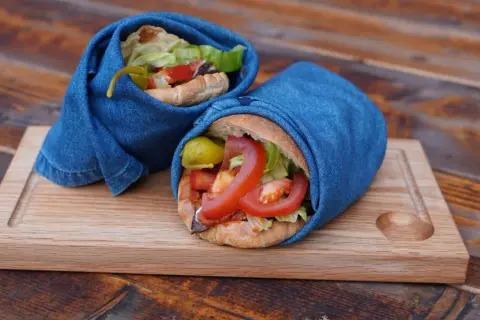 Två kebab i ugn, inslagna i jeans, serveras på en träbricka.