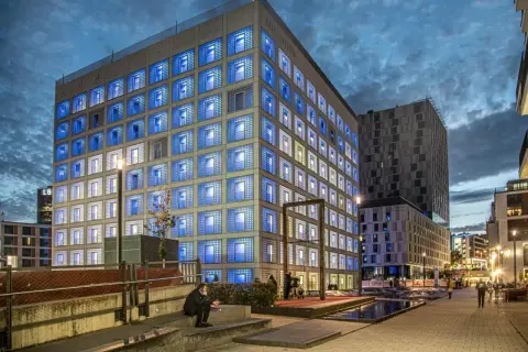 Die Stadtbibliothek Stuttgart leuchtet in der Dämmerung mit blauen Fenstern.