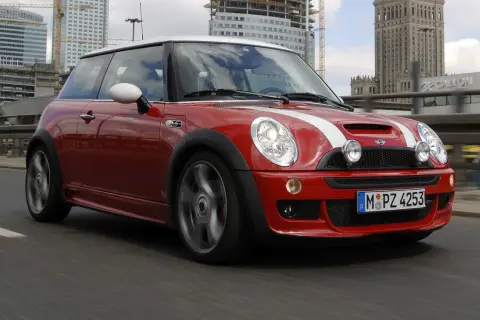 Czerwony Mini R50 z białymi pasami pędzi po moście, w tle nowoczesne budynki i Pałac Kultury.