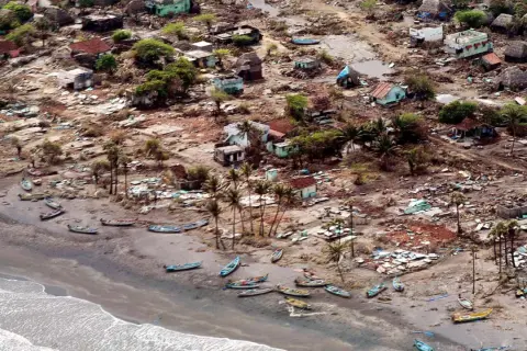 En by ödelagd av tsunamin 2004. Hus är raserade, båtar ligger utspridda på stranden. Bilden ger en känsla av förödelsen och väcker frågan: hur många dog i tsunamin 2004?