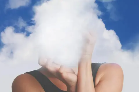 Osoba z twarzą ukrytą w chmurach, symbolizująca mgłę mózgową.