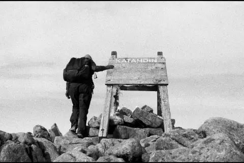 A lone hiker reaches the summit of Katahdin, a testament to perseverance in this striking fine art photography.