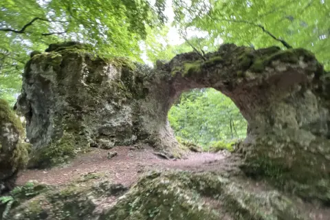 Arco natural cubierto de musgo en la sierra de Entzia, ideal para rutas de senderismo.