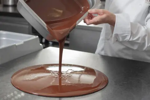 Un chef verse du chocolat fondu. Mycryo, c'est quoi ? C'est la magie du chocolat qui prend forme.