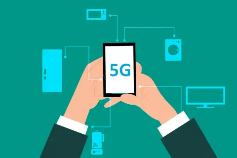 Dłonie trzymają smartfon z napisem 5G, połączony z różnymi urządzeniami domowymi. To pokazuje, co to jest 5G – przyszłość łączności.
