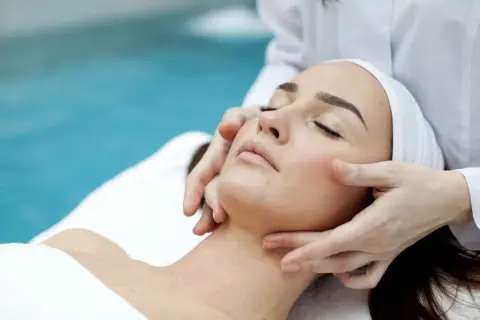 Manos expertas realizan un suave drenaje linfático facial, promoviendo la relajación y el bienestar.