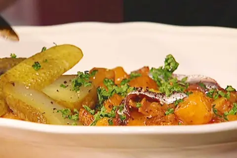 En portion pytt Bellman med stekt potatis, inlagd gurka och ansjovis, toppad med persilja.