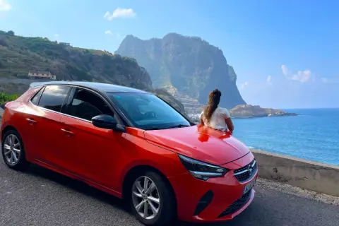Roter Opel auf Madeira, bereit für eine Fahrt entlang der Küste mit Blick auf die dramatischen Berge und das blaue Meer.