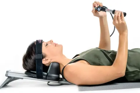 Une femme utilise un appareil pour la traction du cou, allongée sur le dos, avec un bandeau sur la tête.