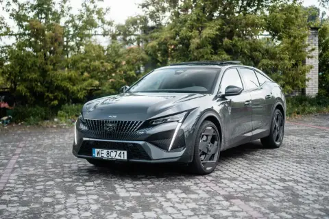 Szary Peugeot 408 na brukowanym podjeździe. Wiele osób szuka peugeot 408 opinie, ten model robi wrażenie.