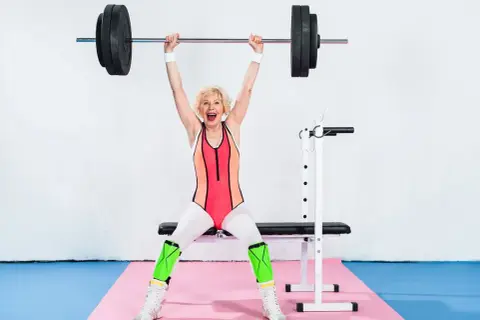 Madeleine Vall Beijner lyfter skivstång över huvudet, glad och stark i gymkläder.