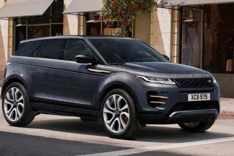 Dunkelgrauer Range Rover Evoque parkt vor einem Geschäft. Goldene Akzente zieren das Fahrzeug.