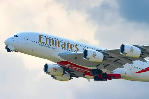 Samolot Emirates wznosi się w powietrze, gotowy do lotu. Zastanawiasz się, ile się leci do Dubaju?