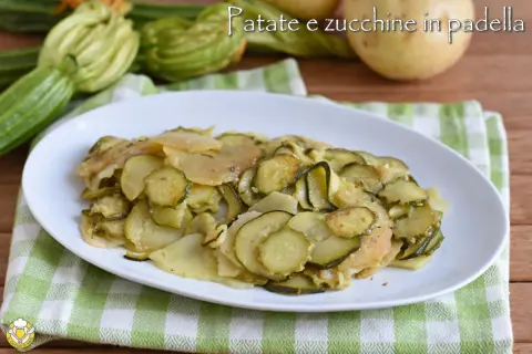 Piatto di zucchine e patate cotte in padella, con zucchine fresche e patate affettate, su un tovagliolo a quadretti verdi.
