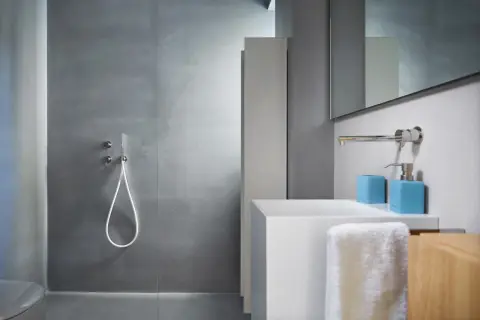 Salle de bain moderne avec douche sans carrelage, lavabo blanc et accessoires bleus.