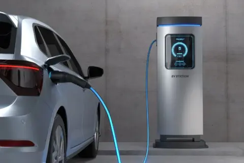 Samochód elektryczny podłączony do stacji ładowania. Sprawdź aktualne ceny ładowania samochodów elektrycznych, aby zaplanować podróż.