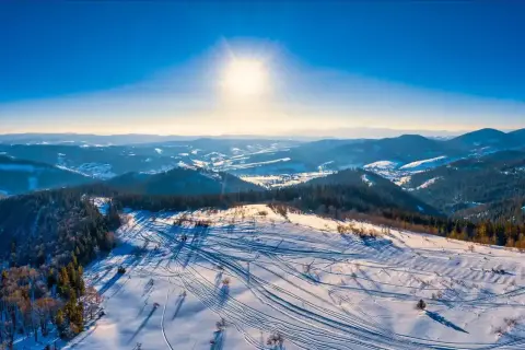 Sonniger Tag im Riesengebirge Skigebiet. Spuren im Schnee zeugen von einem lebhaften Tag auf den Pisten.