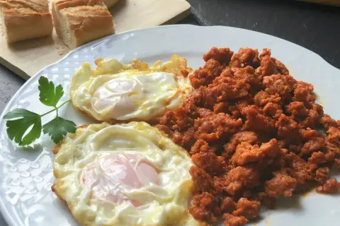 Dos huevos fritos y picadillo de chorizo, ideal para unas deliciosas recetas con picadillo de chorizo. Pan rústico al lado.