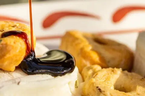 Une délicieuse entrée italienne : des taralli croustillants arrosés de glaçage balsamique sur un lit de fromage frais aux herbes.