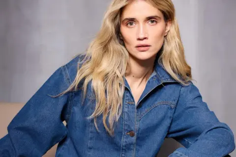Kobieta z blond włosami w dżinsowej kurtce, w ujęciu monochromatycznym.
