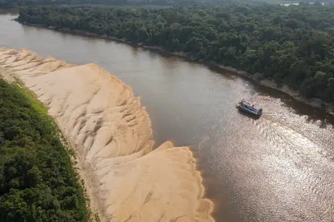 Łódź płynie po szerokiej rzece w Peru, mijając piaszczyste brzegi i gęstą, zieloną dżunglę.