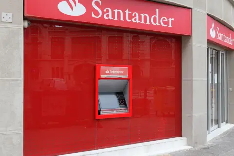 Bankomat Santander Platinum Konserwatywny na czerwonej, lśniącej ścianie.