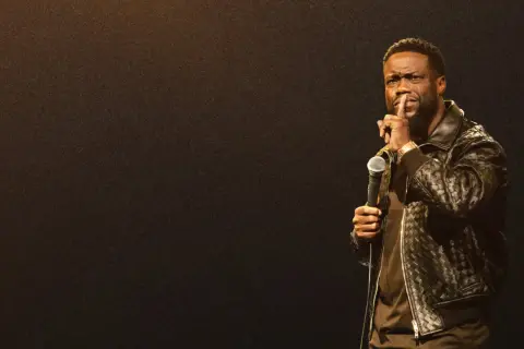 Kevin Hart stand up, trzymając mikrofon i gestykulując do publiczności.