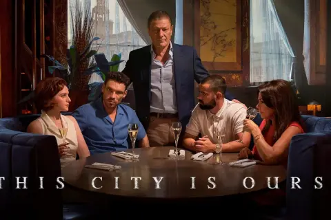 Fünf Personen sitzen an einem runden Tisch in einem eleganten Restaurant. Der Titel "This City Is Ours" deutet auf eine Geschichte über Macht und Einfluss hin.