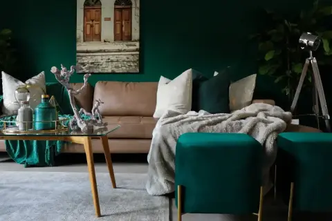 Elegancka, brązowa kanapa w salonie, otoczona zielenią i złotymi dodatkami. Inspiracje dla miłośników luksusowych wnętrz.