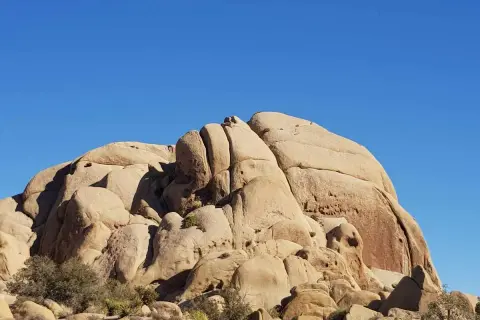 Duże, piaszczyste formacje skalne pod błękitnym niebem w Joshua Tree National Park.
